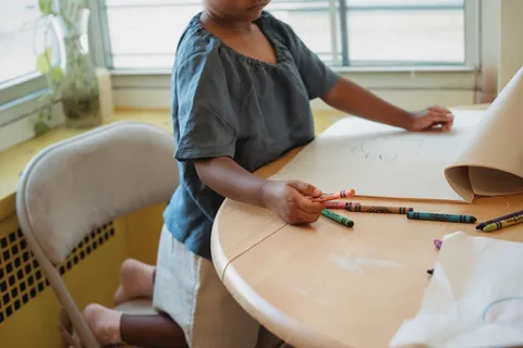 A child drawing on paper with wax crayons