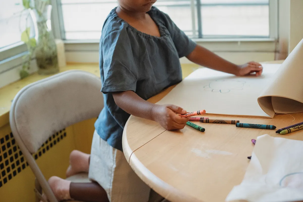 A child drawing on paper with wax crayons