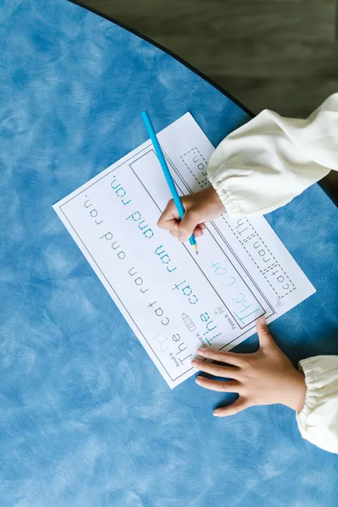 A child writing with a pencil on a workbook page