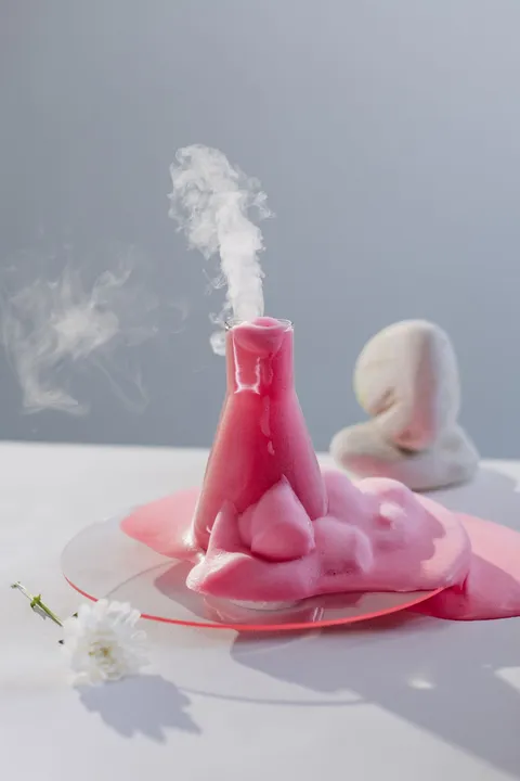 Pink foam bubbling up and out of a glass flask