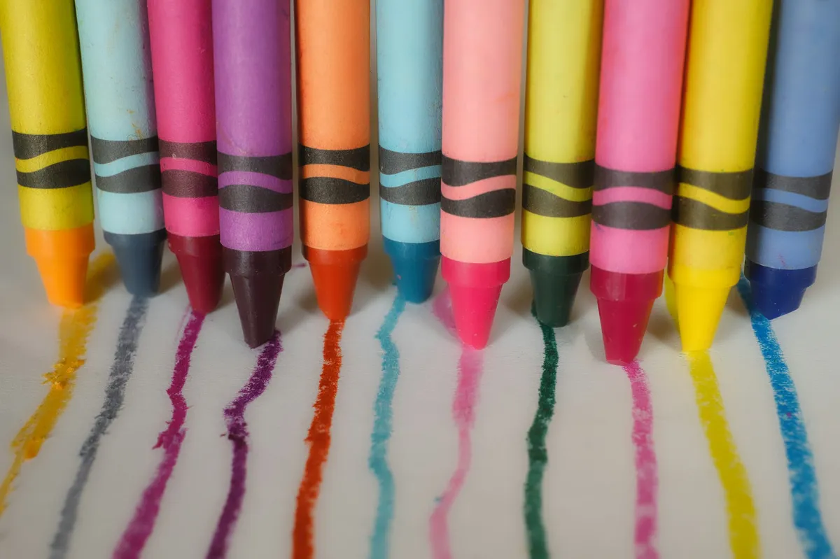 Row of giant colorful crayons drawing bright lines