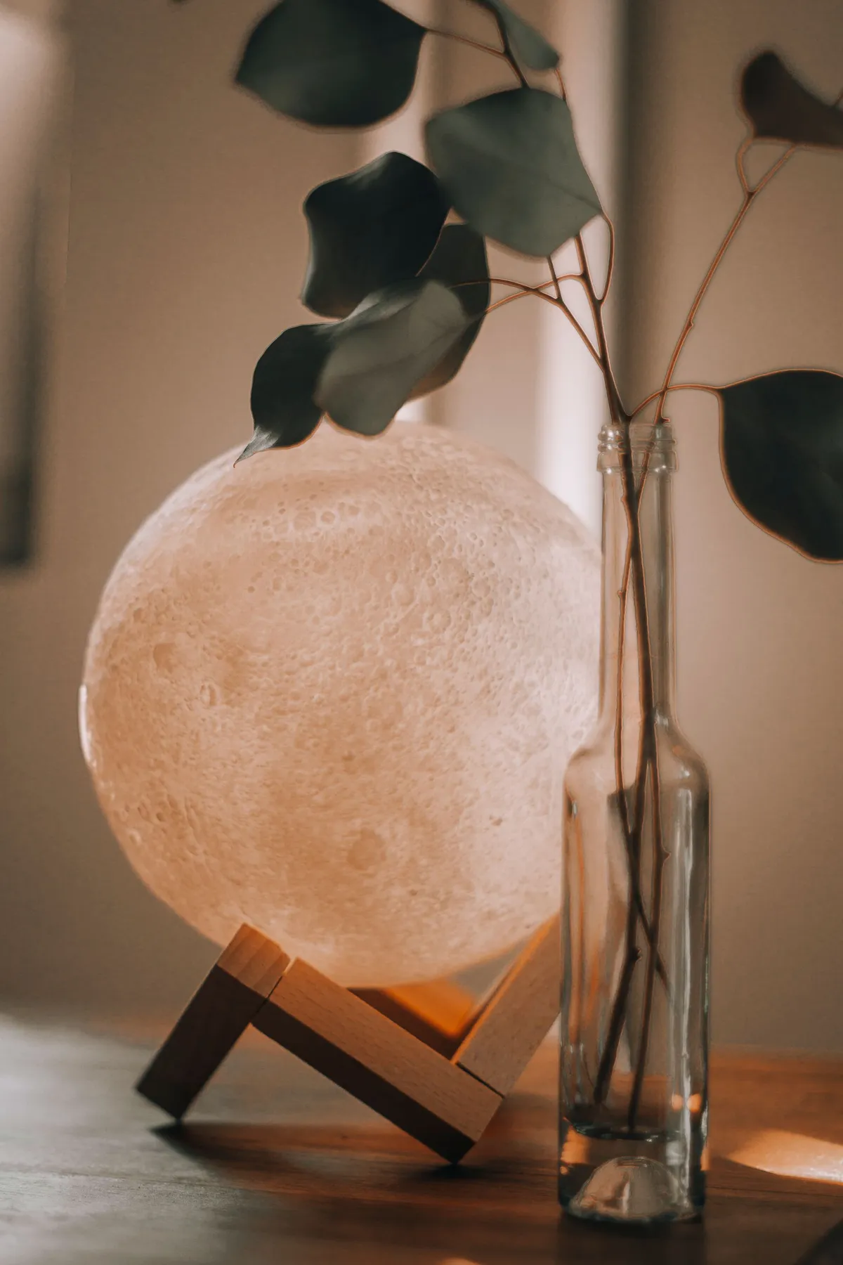 A glowing moon lamp beside a glass vase in a cozy room