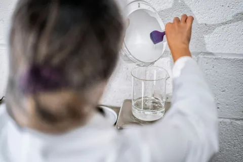 A person holding a glass beaker in a science setting