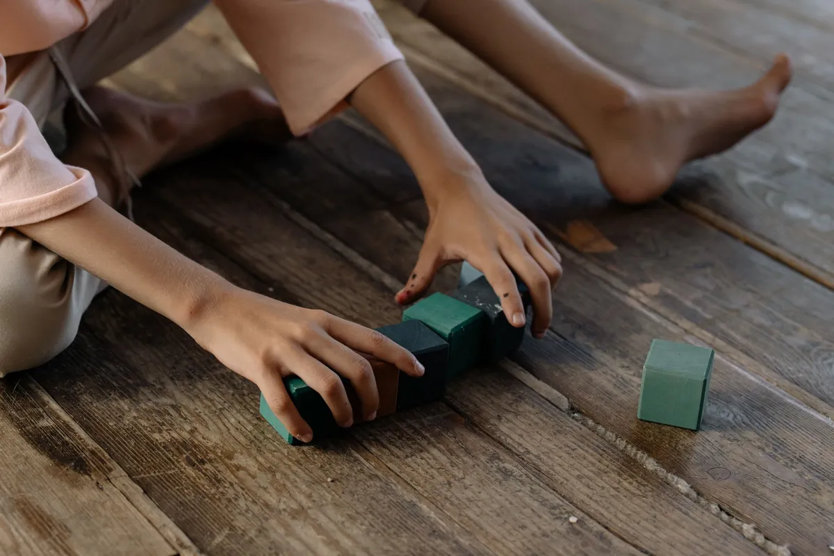 A child playing with colorful building blocks on a wooden floor