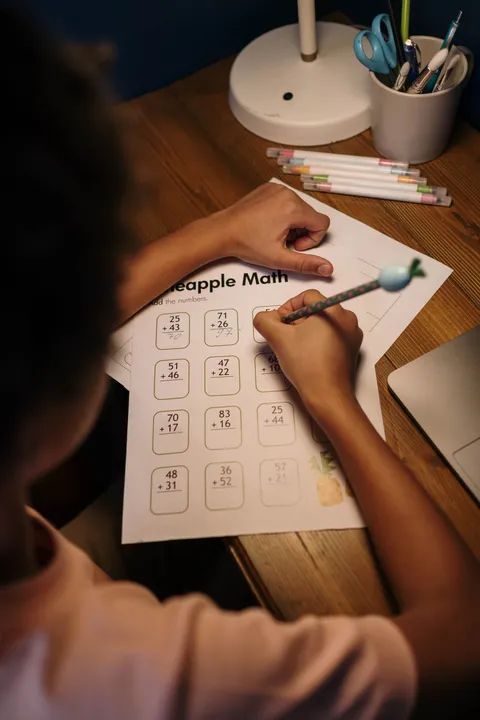 A child working on a math worksheet at a home study desk