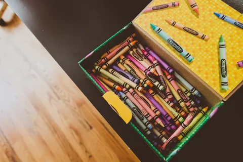 Open box full of crayons on a wooden table