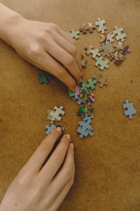 Hands assembling colorful jigsaw puzzle pieces