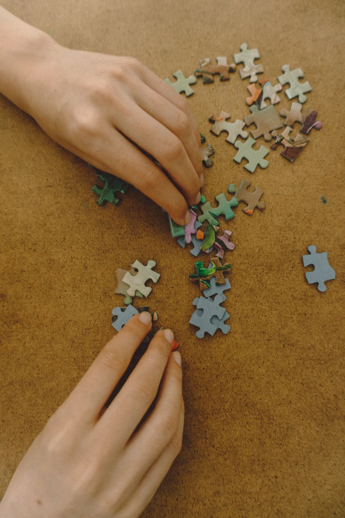 Hands assembling colorful jigsaw puzzle pieces