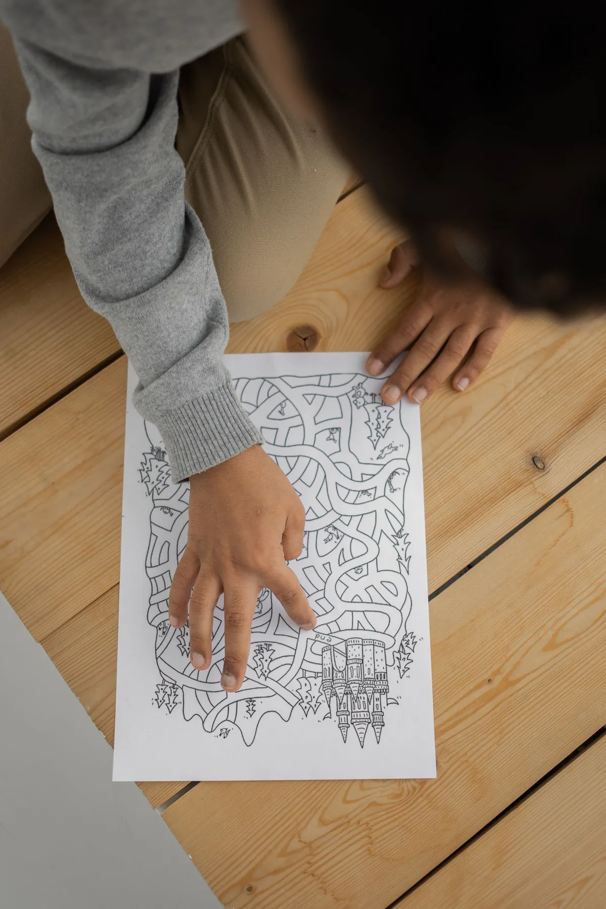 A child sitting on the floor solving a maze puzzle, seen from above