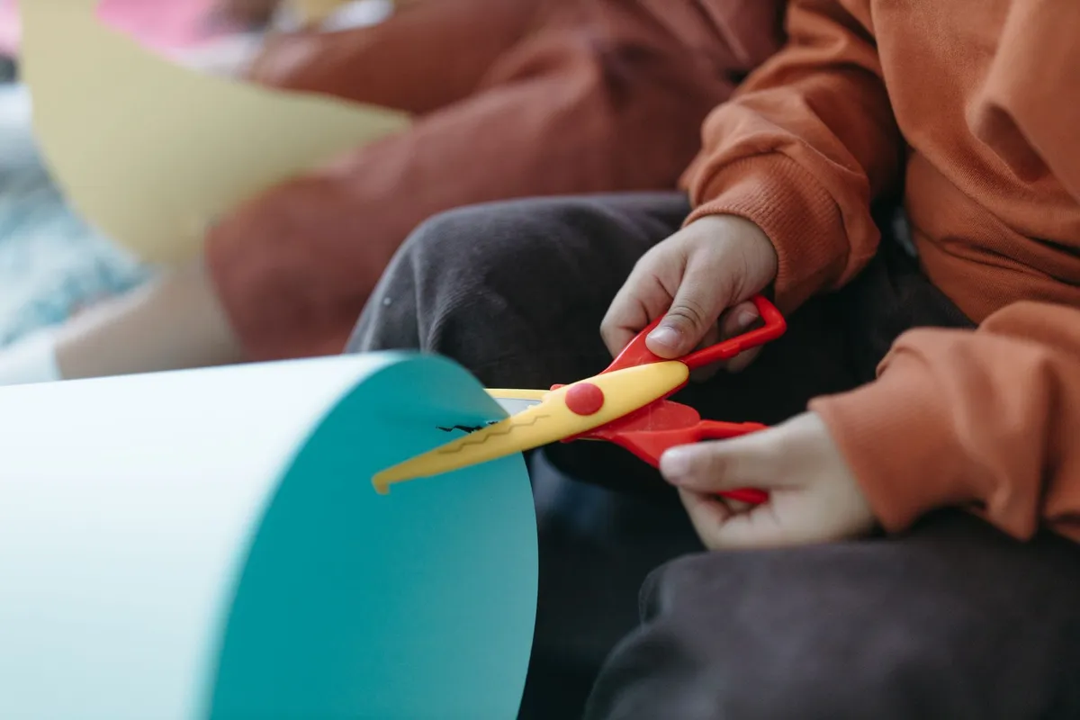 Children using colorful scissors to cut paper