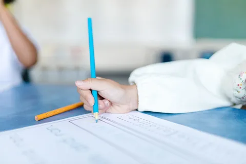 A child drawing on paper with colored pencils
