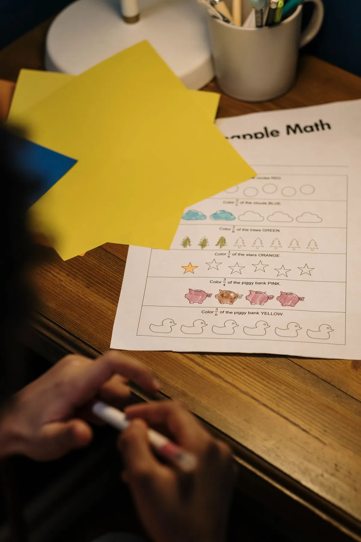 A child working on a simple math worksheet with colorful paper
