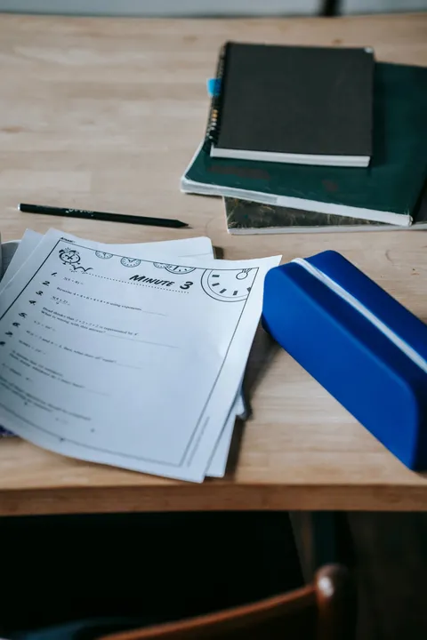 A school desk from above with notebooks, papers and a pen case
