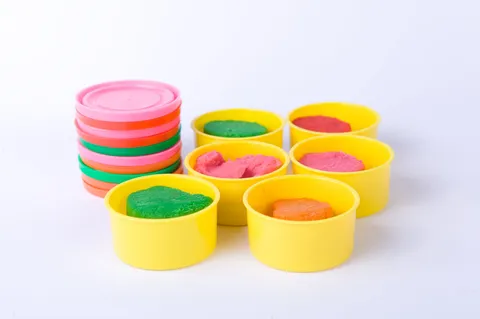 Colorful playdough in yellow containers with pastel lids