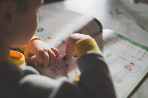 A young child coloring in a workbook