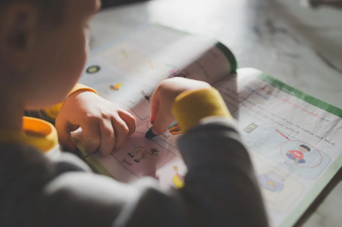 A young child coloring in a workbook