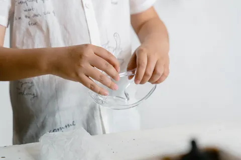 A child's hands holding a clear glass bowl during a science activity